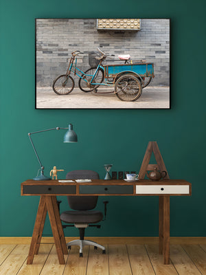 Horizontal colour photograph of a cargo tricycle and bicycle against weathered masonry in Beijing.