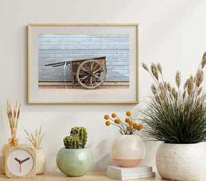 Old wheelbarrow resting against a worn blue wall in Beijing