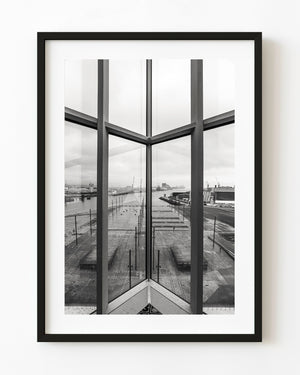 Belfast waterfront seen through tall Titanic Museum windows in black and white