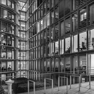 Window grids reveal lit office interiors around a narrow Berlin courtyard
