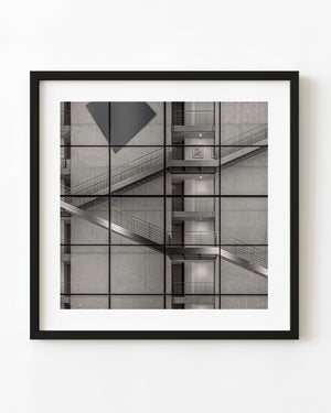 Diagonal stair flights behind a grid of glass panels in Berlin in black and white