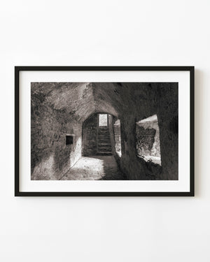 Window light crosses a rough stone hallway at Blarney Castle, Ireland, in black and white.