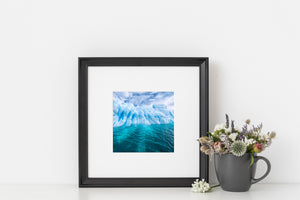 Shadowed openings and layered ridges form an abstract Antarctic seascape.