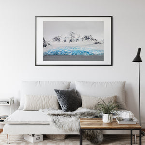 Exposed dark rock breaks through white mountain slopes above coastal ice.