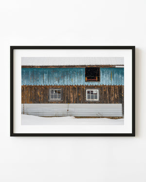 Weathered blue and brown siding on an Ontario barn wall during snowfall.