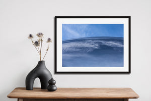 Soft cloud traces contrast with denser reflections below a curved edge.