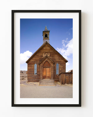 Weathered wooden church in Bodie ghost town, California, beneath blue sky