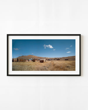 Bodie ghost town buildings across golden grassland beneath a blue sky