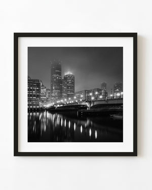 Boston bridge lights and a hazy skyline reflected on water in black and white