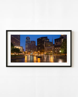 Boston Financial District at dusk with golden lights reflected across a wet plaza
