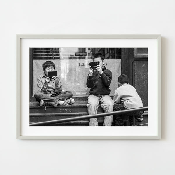 Boys playing video games on a city stoop – black and white