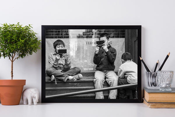 Black and white image of children playing video games on steps