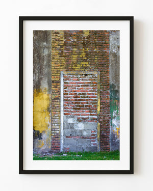Bricked-up doorway within a weathered yellow and green wall.