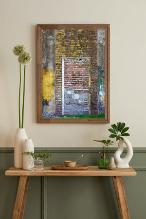Pale door trim surrounds red brick and grey block infill beneath worn yellow paint.