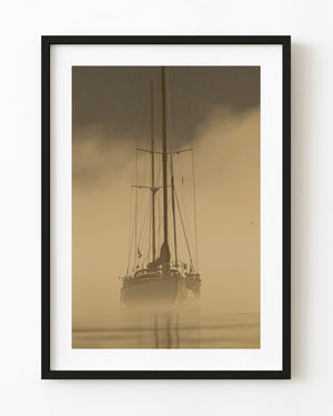 Sailboat emerging through golden mist in British Columbia.