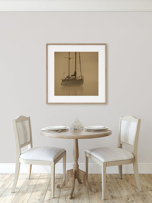 Square colour photograph of a sailboat and its faint reflection in morning mist.