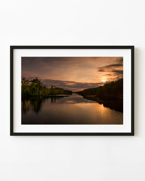 Bronze sunset reflections on the Intracoastal Waterway beneath an orange sky.