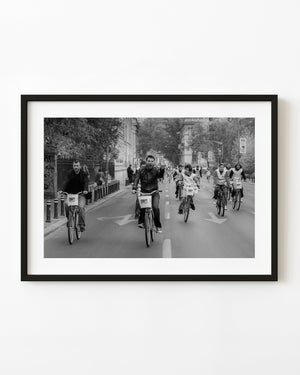 Cyclists riding along a Bucharest street in a black and white photograph.