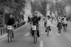 A group of riders approaches the camera along a tree-lined road in Bucharest.