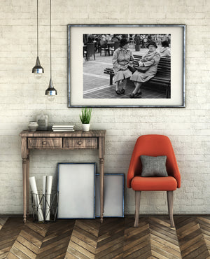 Black and white photograph of everyday city life around a wooden bench.