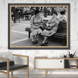 Two women face one another on a bench amid Bucharest café activity.