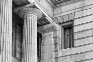 Classical fluted columns beside a window on a Buenos Aires stone facade.