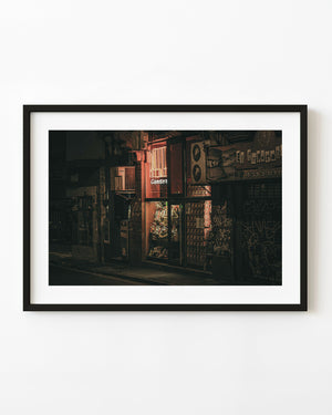 Colour night photograph of a glowing Buenos Aires storefront and graffiti-covered shutter.