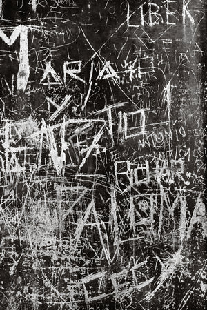 Scratched letters and overlapping graffiti cover a dark Buenos Aires wall.