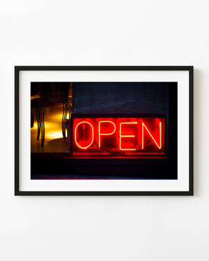Red neon OPEN sign glowing in a Buenos Aires storefront at night.