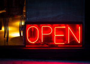 Bright red OPEN lettering contrasts with a dark shop window in Buenos Aires.