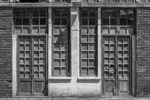 Symmetrical wooden doors and upper windows on a worn Buenos Aires facade.