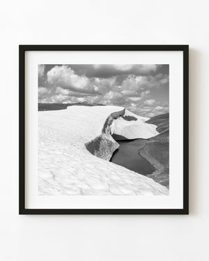 Black and white photograph of Bugaboo snowbanks beside a meltwater pond.