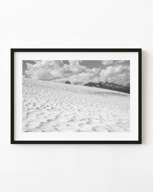 Black and white photograph of textured snowfields and distant Bugaboo mountain peaks.