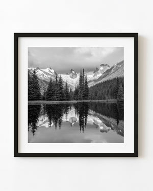 Black and white photograph of Bugaboo mountain peaks reflected in a lake.