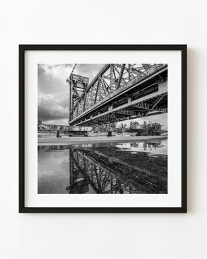 Black and white photograph of Burlington Canal Lift Bridge reflected in a puddle.