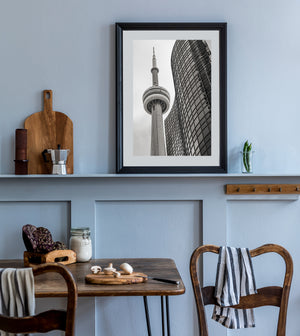 Vertical black and white photograph of the CN Tower and the geometric windows of a neighbouring building.