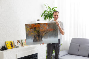 Man met een grote canvasprint van een natuurtafereel in een woonkamer.
