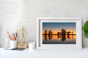 Caddo Lake sunset with scattered cypress trees and soft mirrored reflections.
