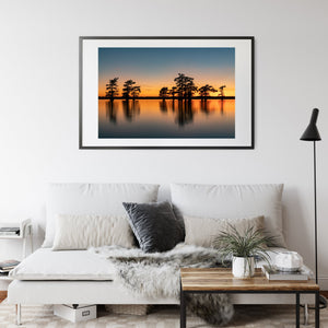 Cypress trees and their reflections form a quiet Caddo Lake sunset landscape.