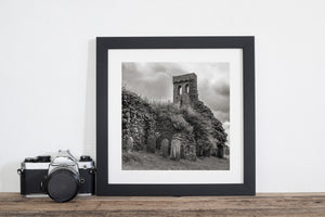 Clouds gather over an old church tower, ivy-covered stonework and grave markers.