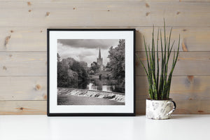 A church spire rises above riverside foliage behind Cahir’s cascading weir.