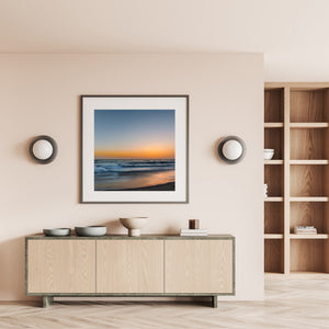 California coastal scene with layered waves, a pale horizon and warm evening reflections.