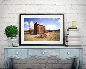 California ghost town scene with aged buildings and scattered clouds above.