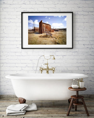 Sunlight reveals rough wood, old structures and golden ground in an Old West landscape.