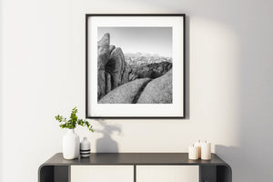 Weathered rock formations rise beside broad granite surfaces beneath a cloudy sky.