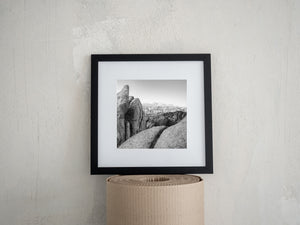 Light and shadow define rugged boulders against a distant alpine ridge.
