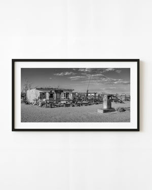 Black and white photograph of a lone fuel pump beside an abandoned Route 66 station in California.