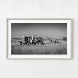 Black and white photograph of vintage tractor and seeder in tall prairie grass Alberta