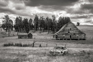 Weathered wooden barn beneath heavy clouds in rural British Columbia