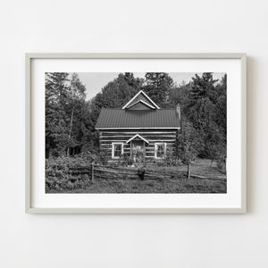 Black and white photograph of a historic Ontario log cabin surrounded by forest
